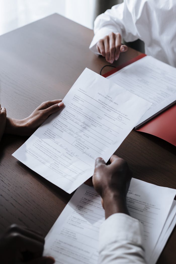 services-01 Adults reviewing legal documents on a wooden desk indoors, highlighting professional collaboration.